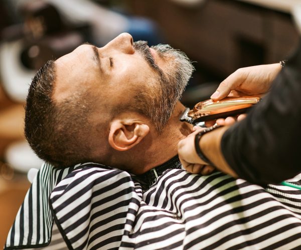 Barber trims the beard of the customer